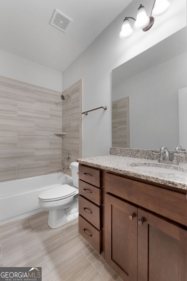 full bathroom with tiled shower / bath, vanity, and toilet