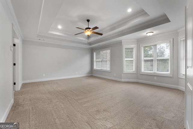 carpeted spare room with a tray ceiling, ornamental molding, and ceiling fan