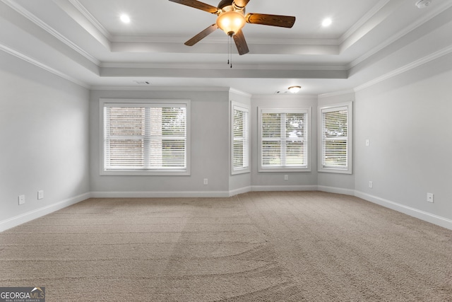 carpeted spare room with a raised ceiling, crown molding, and ceiling fan