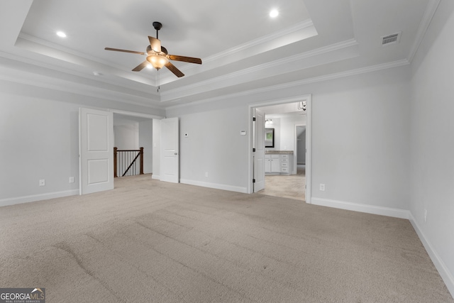 unfurnished living room with crown molding, light carpet, ceiling fan, and a tray ceiling