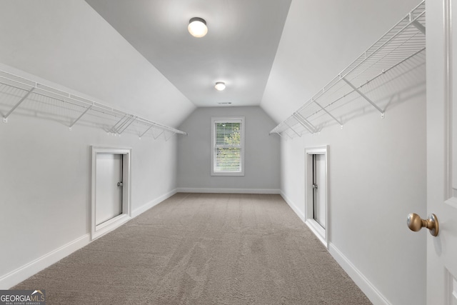 spacious closet with light colored carpet and vaulted ceiling