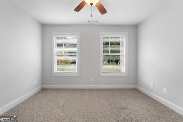 empty room featuring plenty of natural light, ceiling fan, and carpet flooring