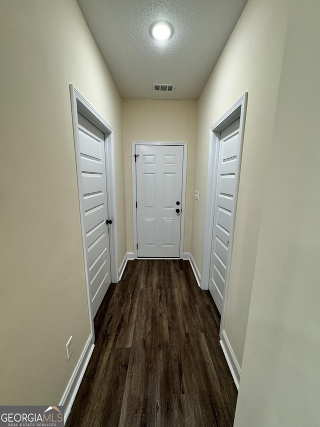 hallway featuring dark wood-type flooring and a textured ceiling