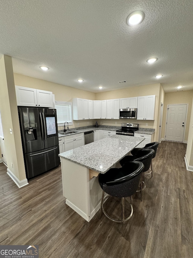 kitchen featuring sink, a breakfast bar area, a kitchen island, stainless steel appliances, and white cabinets