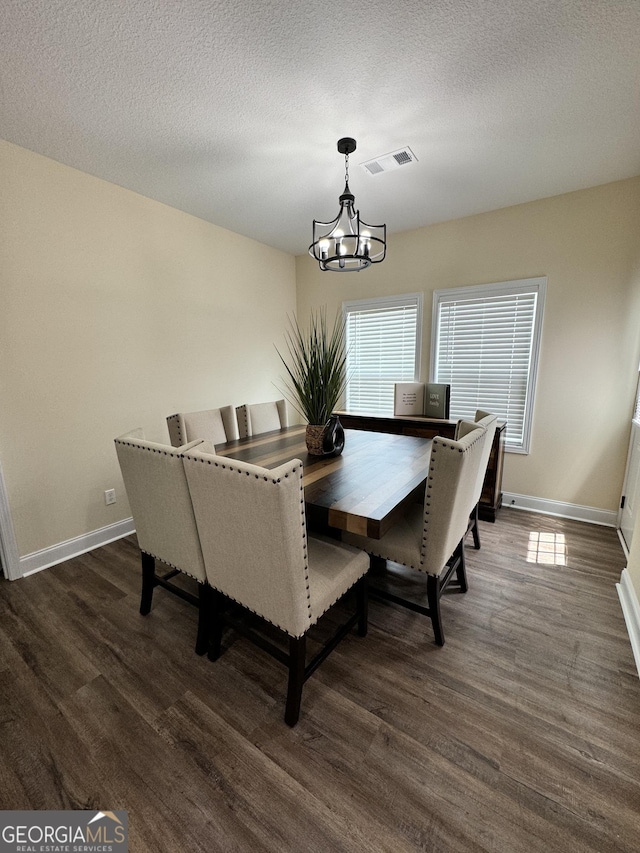 dining room featuring a textured ceiling, dark wood-type flooring, and a chandelier