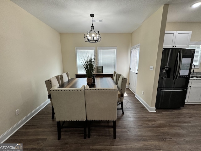 dining space with dark wood-type flooring and an inviting chandelier