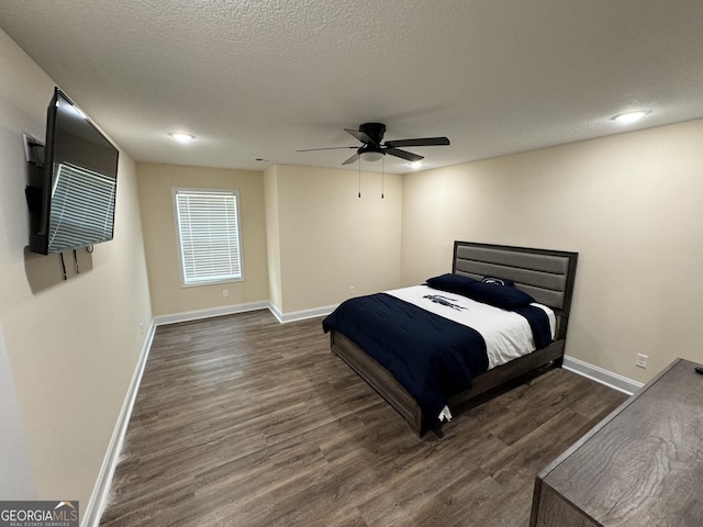 bedroom with ceiling fan, dark wood-type flooring, and a textured ceiling