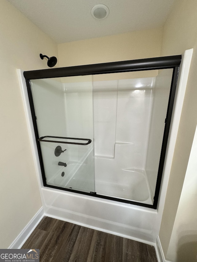 bathroom featuring wood-type flooring and enclosed tub / shower combo