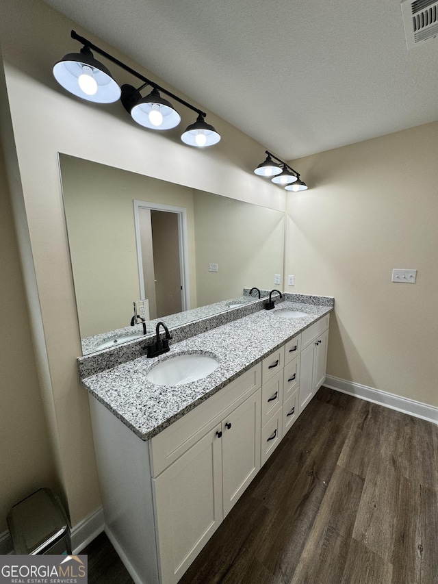 bathroom featuring wood-type flooring, vanity, and a textured ceiling