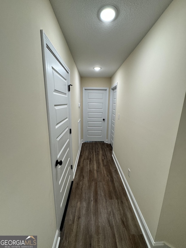 corridor featuring dark wood-type flooring and a textured ceiling