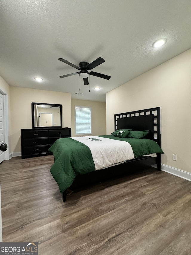 bedroom with hardwood / wood-style flooring, ceiling fan, and a textured ceiling