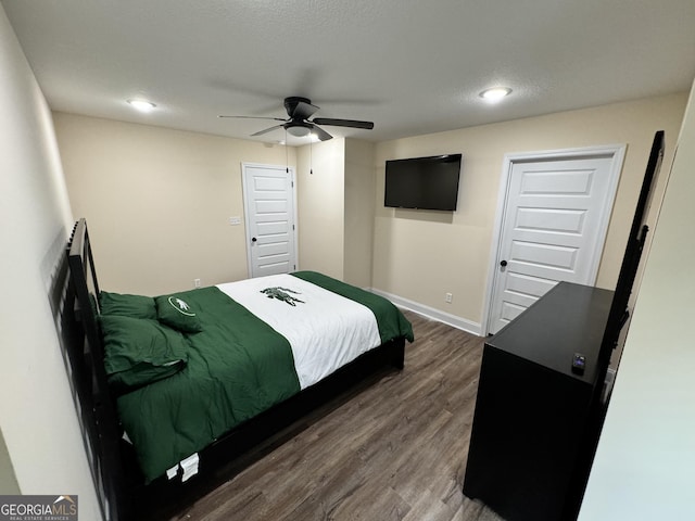 bedroom with ceiling fan, a textured ceiling, and dark hardwood / wood-style flooring