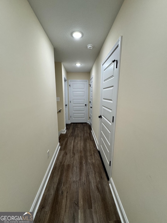 hallway with dark hardwood / wood-style flooring and a textured ceiling