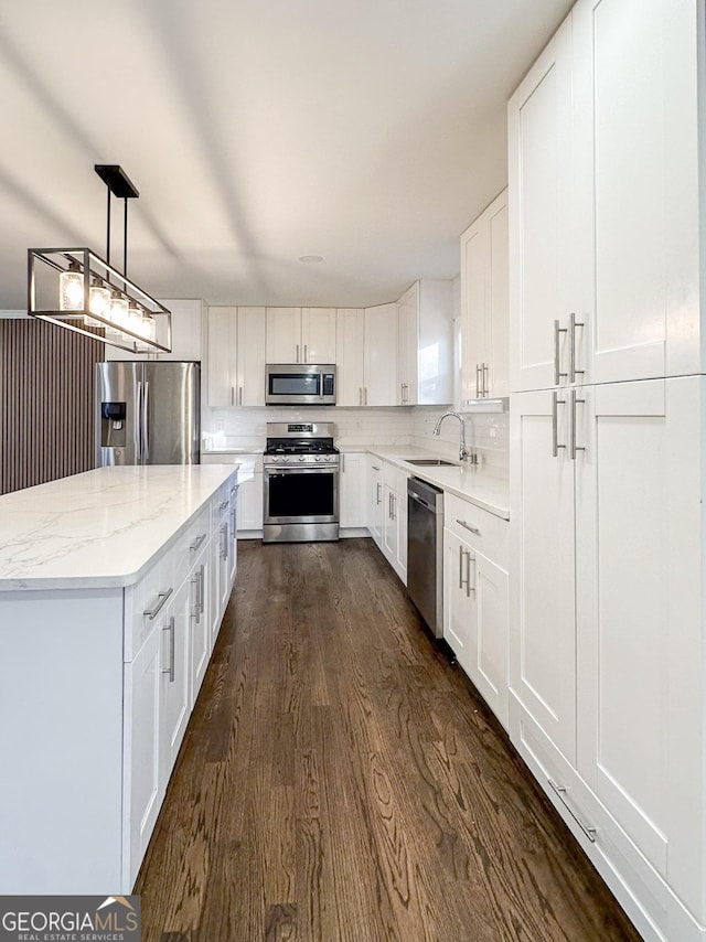 kitchen with white cabinetry, sink, stainless steel appliances, and hanging light fixtures