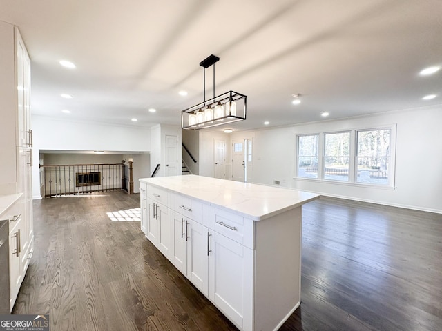 kitchen featuring white cabinetry, a center island, dark hardwood / wood-style flooring, pendant lighting, and light stone countertops