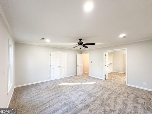 unfurnished bedroom featuring crown molding, ceiling fan, light carpet, and a closet