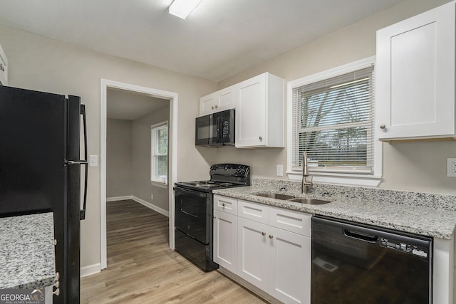 kitchen featuring white cabinetry, sink, light hardwood / wood-style floors, black appliances, and light stone countertops