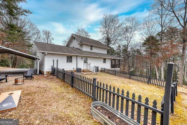 rear view of property featuring cooling unit and a yard