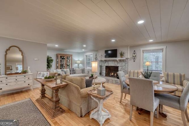 living room featuring a fireplace, light hardwood / wood-style flooring, and wooden ceiling