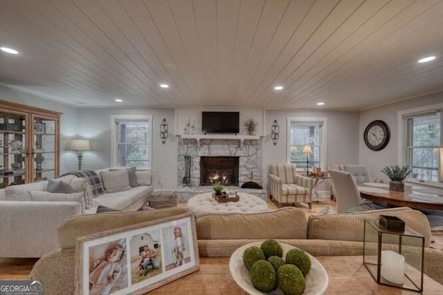 living room featuring crown molding, wooden ceiling, a fireplace, and light hardwood / wood-style flooring