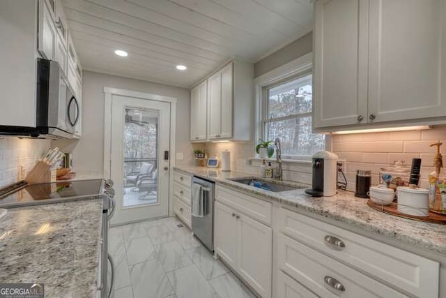 kitchen featuring tasteful backsplash, white cabinetry, sink, light stone counters, and stainless steel appliances