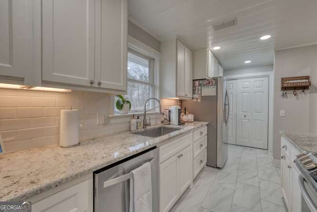 kitchen with sink, light stone counters, range, dishwasher, and white cabinets