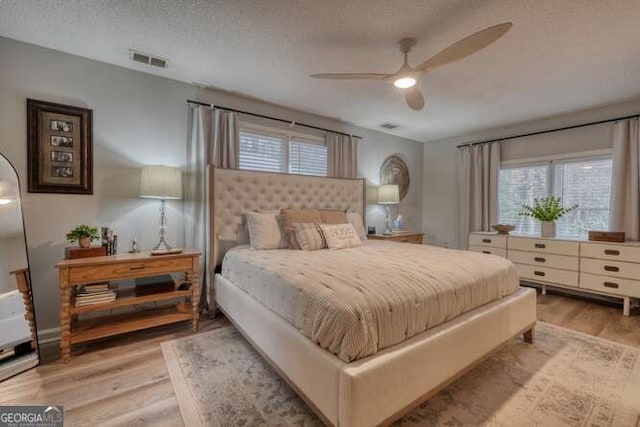 bedroom with ceiling fan, a textured ceiling, and light hardwood / wood-style flooring