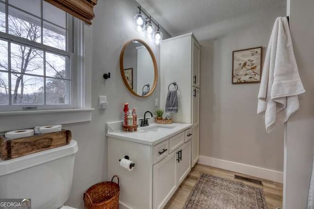 bathroom featuring vanity, hardwood / wood-style flooring, a textured ceiling, and toilet