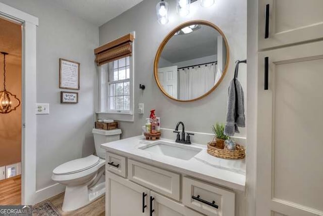 bathroom featuring an inviting chandelier, vanity, toilet, and wood-type flooring