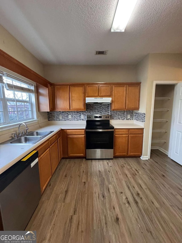 kitchen featuring appliances with stainless steel finishes, sink, light hardwood / wood-style floors, and decorative backsplash