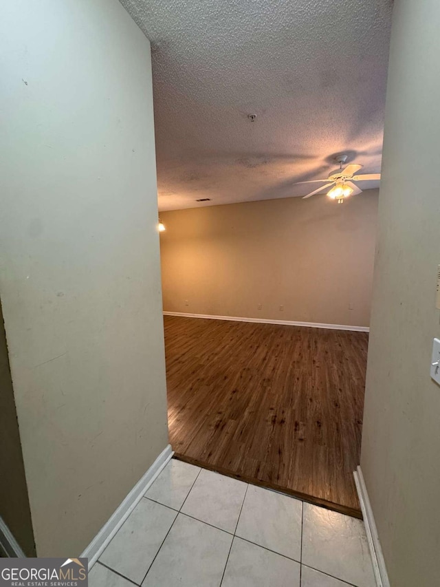 empty room featuring light tile patterned flooring, ceiling fan, and a textured ceiling