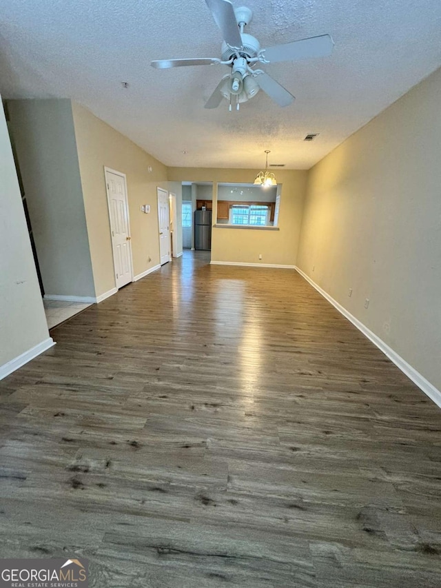 unfurnished living room featuring dark hardwood / wood-style floors, a textured ceiling, and ceiling fan