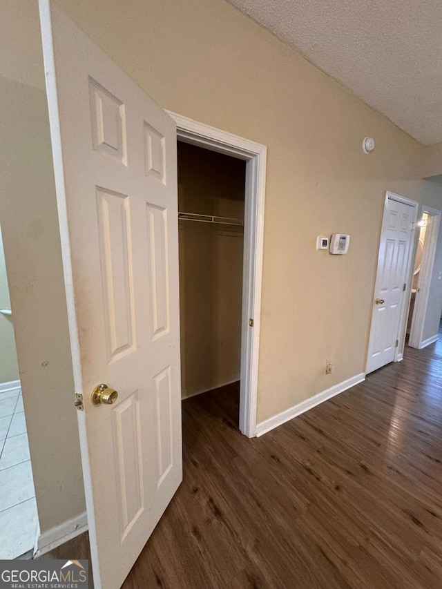 unfurnished bedroom featuring vaulted ceiling, dark wood-type flooring, a textured ceiling, and a closet