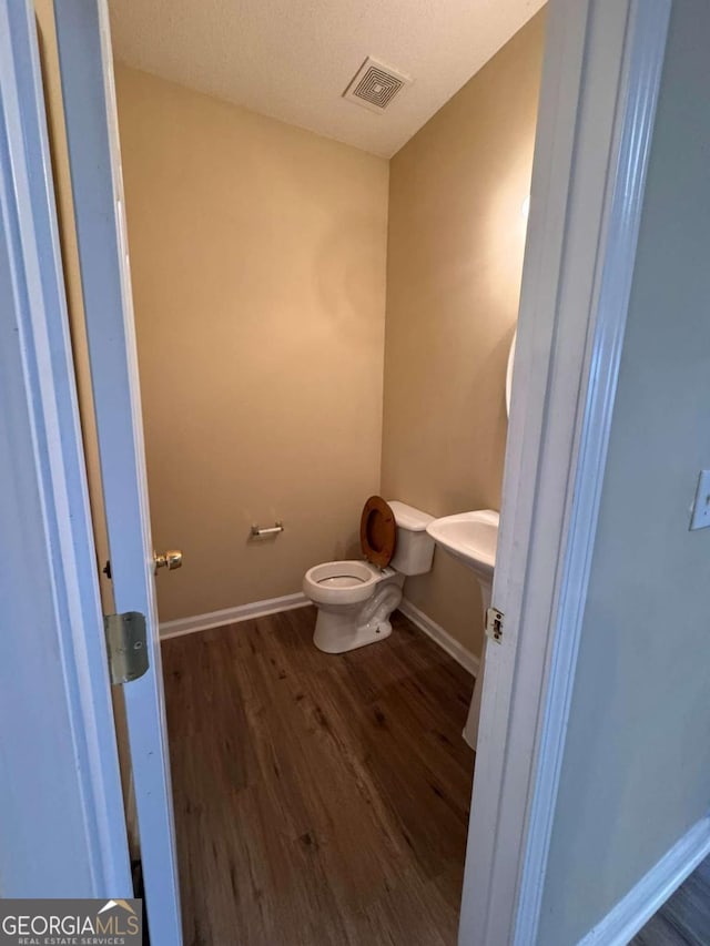 bathroom with wood-type flooring and toilet