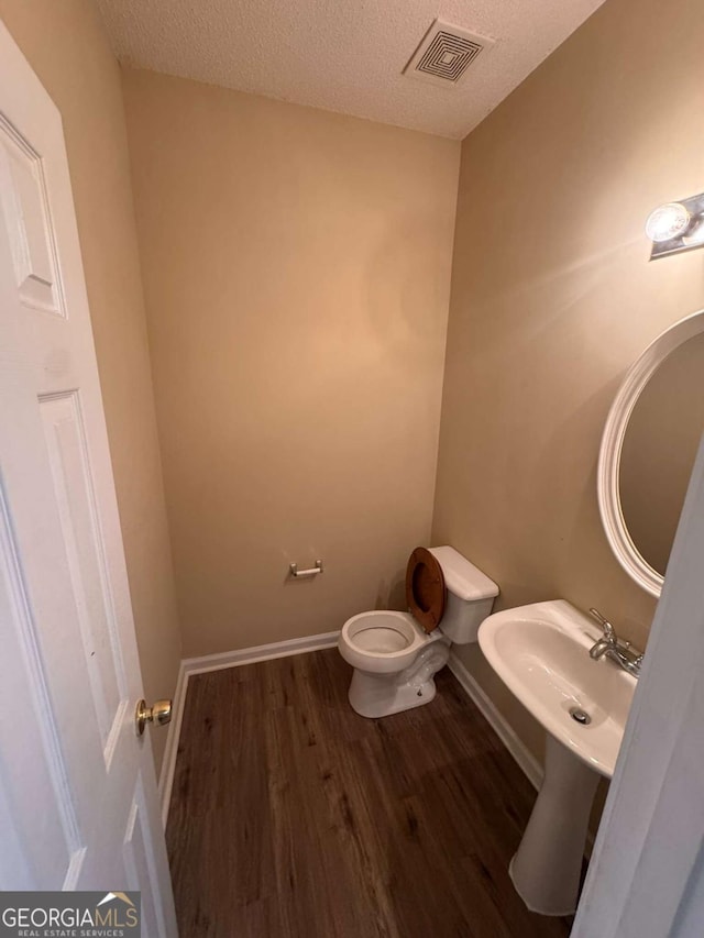 bathroom featuring sink, a textured ceiling, wood-type flooring, and toilet