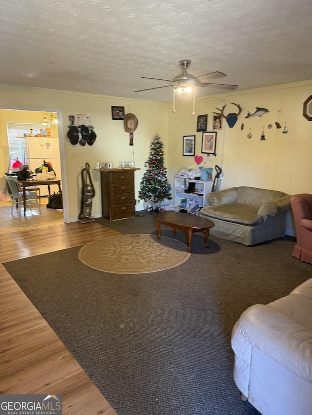 living room featuring ceiling fan, hardwood / wood-style floors, and a textured ceiling