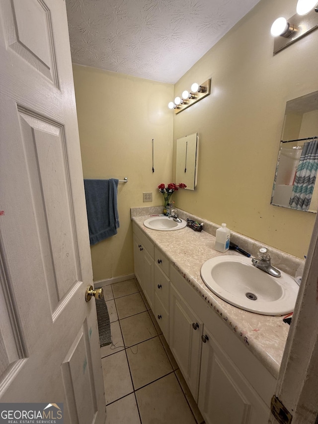 bathroom with tile patterned flooring, vanity, and a textured ceiling