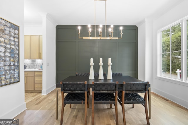 dining space featuring crown molding, light hardwood / wood-style floors, and a notable chandelier