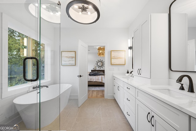 bathroom with tile patterned floors, vanity, a wealth of natural light, and a washtub