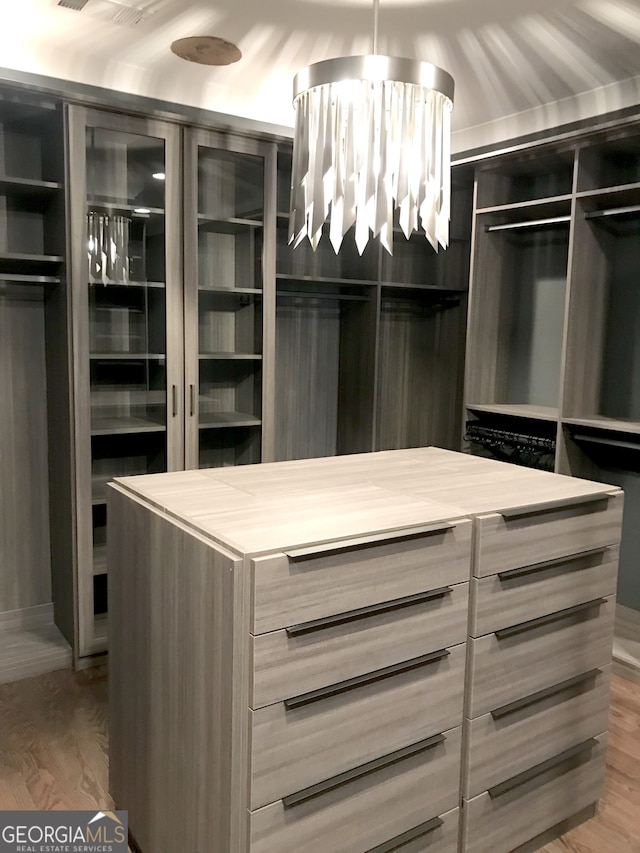 walk in closet with an inviting chandelier and hardwood / wood-style flooring