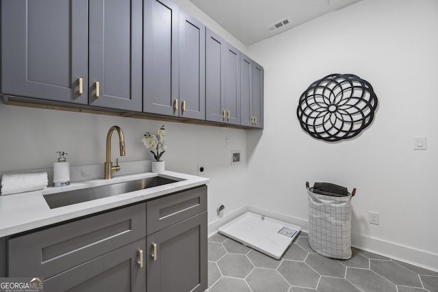 laundry area featuring sink, dark tile patterned floors, electric dryer hookup, hookup for a washing machine, and cabinets