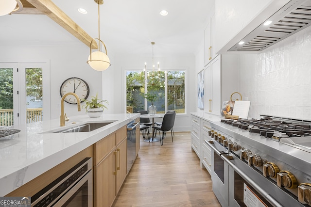 kitchen with ventilation hood, sink, white cabinets, hanging light fixtures, and stainless steel appliances