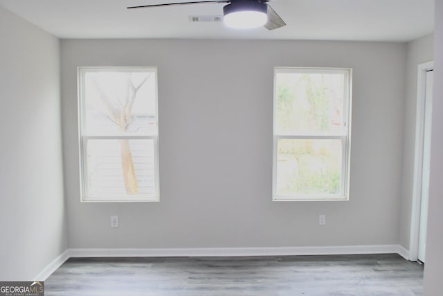 spare room featuring visible vents, baseboards, ceiling fan, and wood finished floors