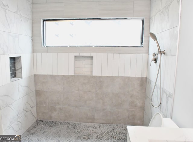 bathroom featuring a wealth of natural light and tiled shower