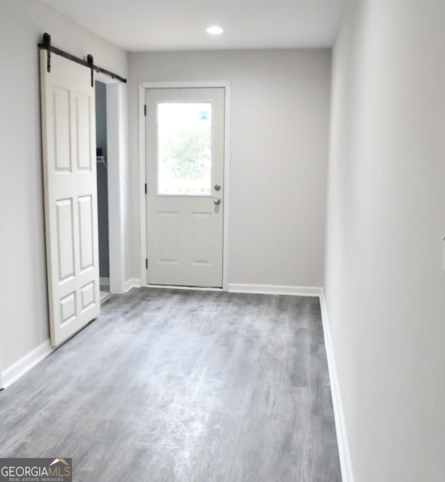 doorway with recessed lighting, a barn door, baseboards, and wood finished floors