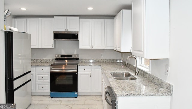 kitchen with white cabinets, light stone countertops, appliances with stainless steel finishes, and a sink