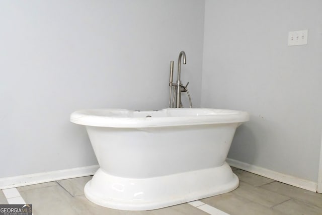 bathroom with a soaking tub and baseboards