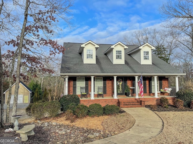 new england style home with an outbuilding, a garage, and a porch