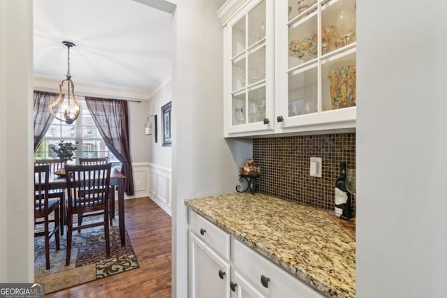 interior space featuring dark hardwood / wood-style flooring, decorative light fixtures, light stone countertops, and white cabinets