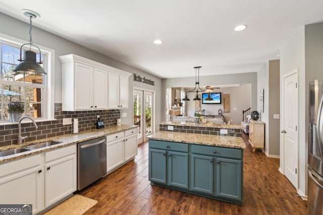 kitchen featuring white cabinetry, sink, decorative light fixtures, and appliances with stainless steel finishes